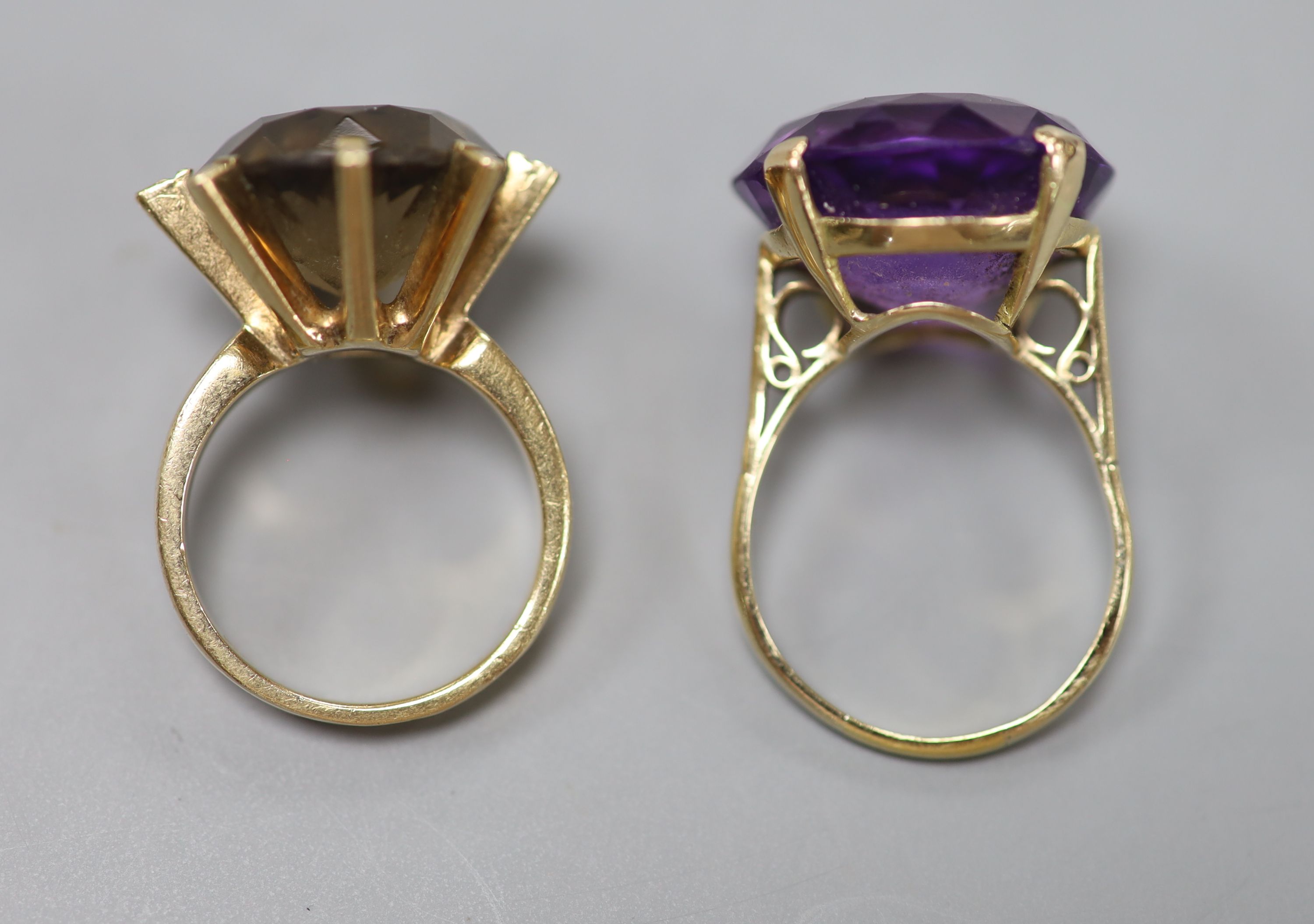 A modern yellow metal and amethyst dress ring and a similar smoky quartz ring, gross 15.2 grams.